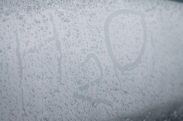 H2O water symbol on car glass in rain