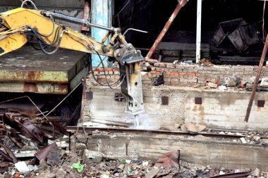 Hidrolik çekiçli modern güçlü kazıcı binayı yıkıyor.