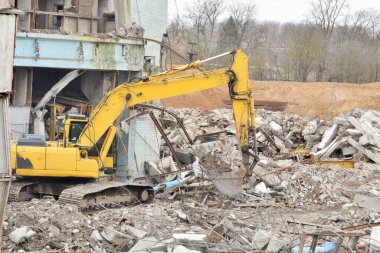 Modern, güçlü bir kazıcı yıkılmış bir binanın enkazını temizliyor.