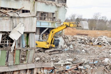 Modern, güçlü bir kazıcı yıkılmış bir binanın enkazını temizliyor.