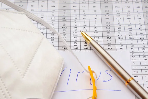 Koruyucu tıbbi giysi istatistiksel tablolarda ve yazılı virüslü kağıtta yatıyor.
