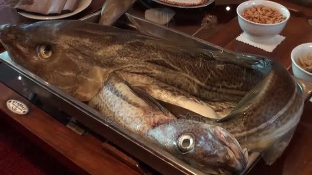 Baked sea fish on a baking sheet on a wooden background. Iceland. — Stock Video