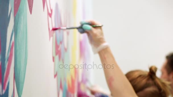 Pittura a mano ragazza con pennelli e vernice sul muro. Tiro lento . — Video Stock