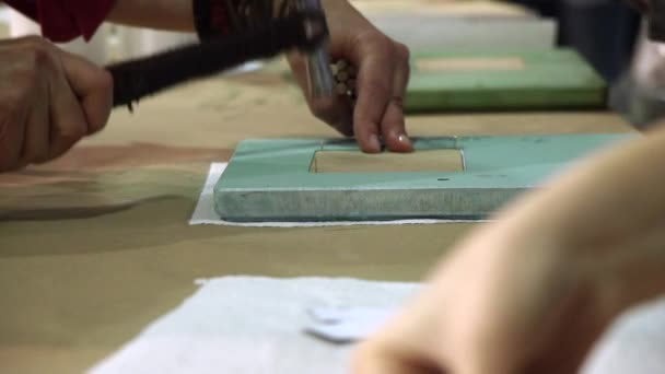 Рука дизайнера молотка в нігті в фоторамку в творчій майстерні . — стокове відео