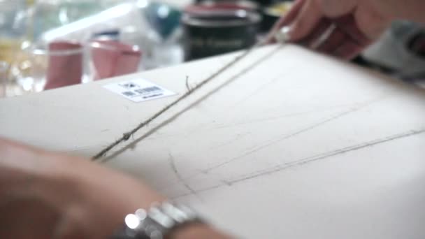 Дизайнер украшает бумагу верёвкой. Процесс в профессиональной студии дизайна . — стоковое видео