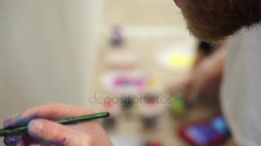 El fırçalar arka plan rengine katta duvar boyar. Ağır çekim.