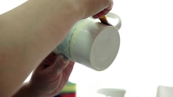 Dessine à la main avec un pinceau et peint sur une tasse en céramique. Atelier créatif . — Video