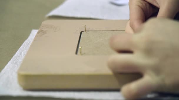 Hand of designer inserts a the nail in the photo frame in a creative workshop. — Stock Video