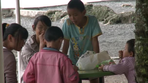 Niños jugando en gazebo con techo de paja en la orilla del lago en las montañas . — Vídeos de Stock