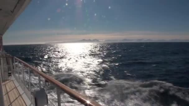 Schneebedeckte Berge vor dem Hintergrund von Wellen. Blick vom Schiff aus. — Stockvideo