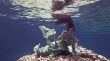 Genç kız modeli sualtı pozlar mercanlar Kızıldeniz içinde arka plan üzerinde kamera için.