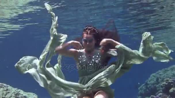 Genç kız modeli sualtı pozlar mercanlar Kızıldeniz içinde arka plan üzerinde kamera için. — Stok video