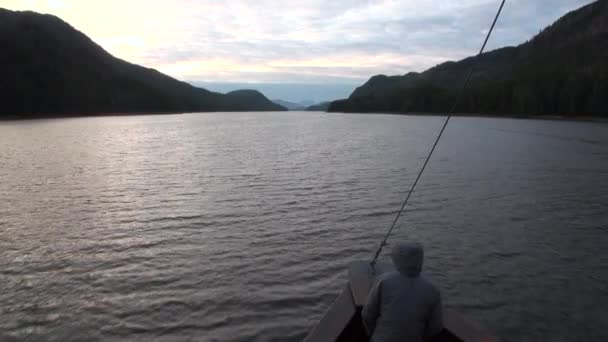 Az ember a hajó vitorlák nyugodt víz a Csendes-óceán Alaszkában háttér partján. — Stock videók