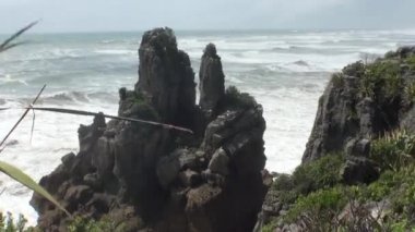 Dalgalar bir kayalık sahil ve dağların Yeni Zelanda.