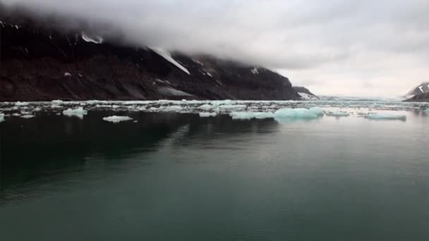 Bewegte Eisschollen auf dem Hintergrund des Berges auf dem Wasser des arktischen Ozeans in Spitzbergen. — Stockvideo