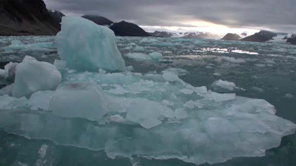 Bewegte Eisschollen auf dem Hintergrund des Berges auf dem Wasser des arktischen Ozeans in Spitzbergen. — Stockvideo