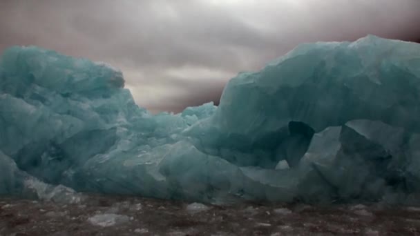 Eisberg im Wasser des arktischen Ozeans auf dem Hintergrund des Berges in Spitzbergen. — Stockvideo