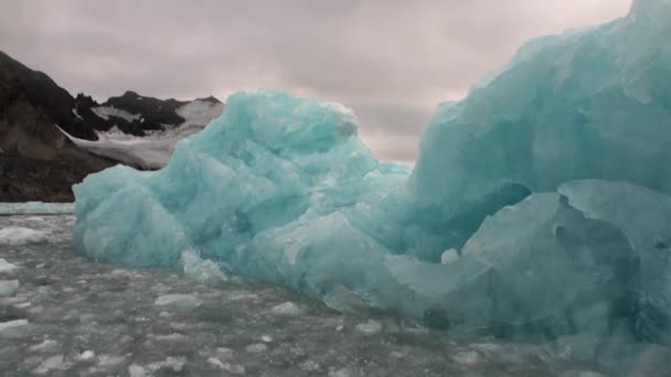 Айсберг в водах Северного Ледовитого океана на фоне горы на Шпицбергене . — стоковое видео