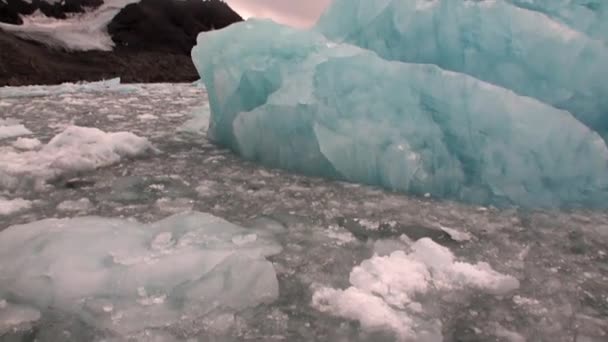 Eisberg im Wasser des arktischen Ozeans auf dem Hintergrund des Berges in Spitzbergen. — Stockvideo