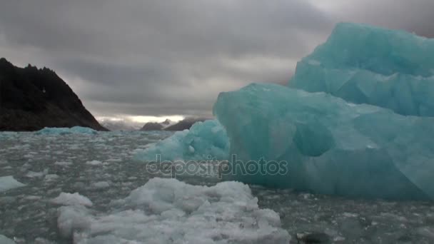 Isberg i vattnet i norra ishavet på bakgrund av berg i Svalbard. — Stockvideo