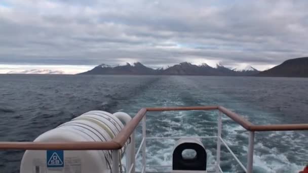 Atrás del barco en el agua del Océano Ártico en el fondo de la montaña en Svalbard . — Vídeo de stock