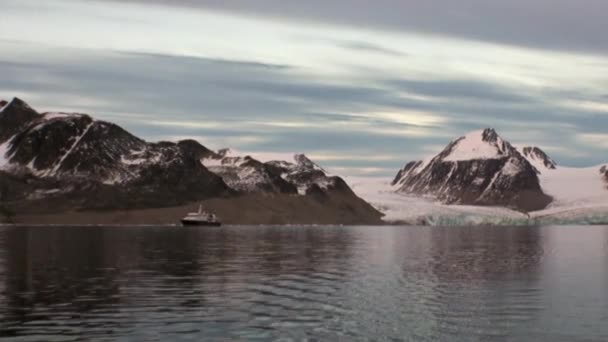 Ship in water of Arctic Ocean on background of of snow mountains in Svalbard. — Stock Video