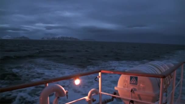 Atrás del barco por la noche sobre el fondo de la montaña sobre el agua del Océano Ártico . — Vídeos de Stock