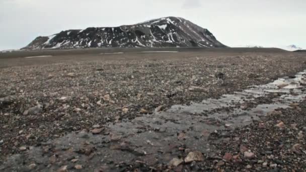 Steine nach dem Schmelzen von Eis und Schnee auf dem Hintergrund des Berges in Spitzbergen. — Stockvideo