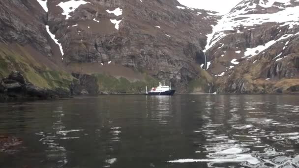 Schip in de buurt van de waterval in rotskust en bergen van Falklandeilanden. — Stockvideo