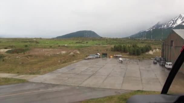 Ελικόπτερο πετά προς το ελικοδρόμιο στο χιόνι και το καταπράσινο βουνό της Νησιά Φώκλαντ. — Αρχείο Βίντεο