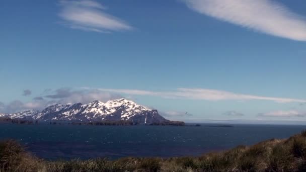 Zasněžené hory na pozadí modré oblohy s mraky a oceán v Antarktidě. — Stock video