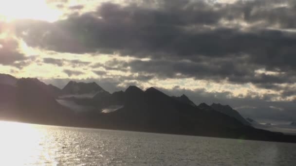 Puesta de sol en el fondo de las montañas y la superficie del agua en el océano helado del Ártico . — Vídeo de stock