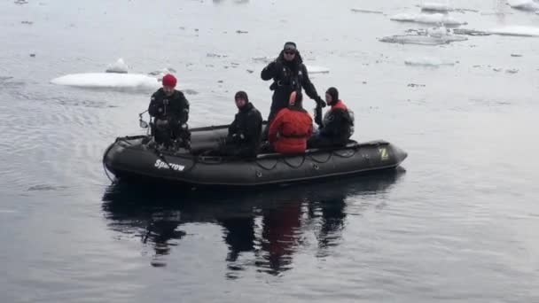 Schlauchboot mit Menschen auf dem Hintergrund von Eisbergen, Eis, im arktischen Ozean. — Stockvideo