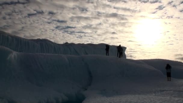Menschen auf einem riesigen Eisberg vor dem Hintergrund weißer Wolken im arktischen Ozean. — Stockvideo