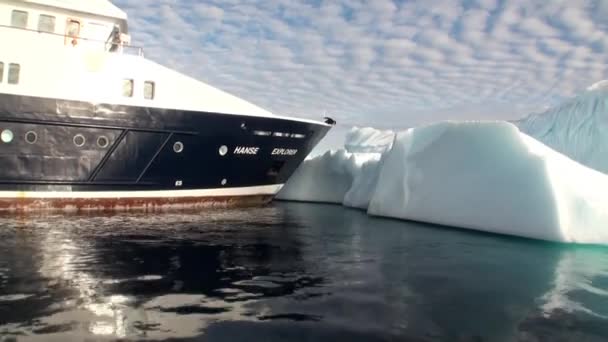 Person on bow ship looking down at water beside iceberg in ocean in Arctic. — Stock Video