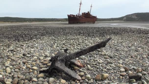 Rusty wreckage shipwreck and anchor on deserted shore beneaped dried-up ocean. — Stock Video