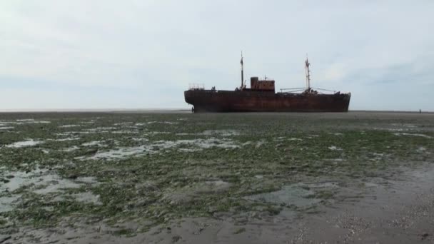 Rusty wreckage shipwreck on deserted shore beneaped dried-up ocean. — Stock Video