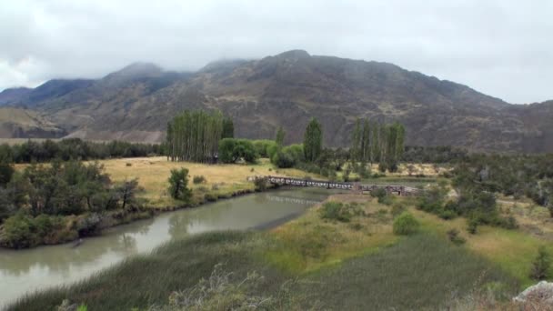 Puente sobre la calma sucia de río de montaña en Patagonia Argentina . — Vídeos de Stock