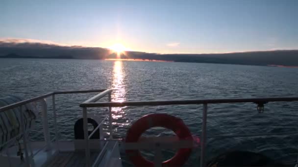 Baksidan av fartyget i vattnet i norra ishavet på bakgrund av berg i Svalbard. — Stockvideo