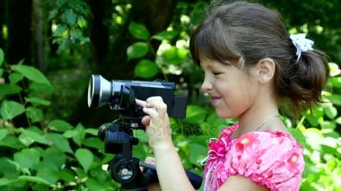 Genç kız video kamera ile film üzerinde yeşil park yavaş hareket doğada vuruyor.