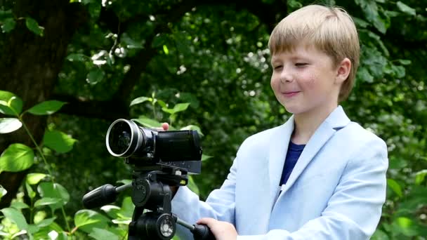 少年はスローモーションの緑豊かな公園の自然についてのビデオ撮影映画に見える. — ストック動画