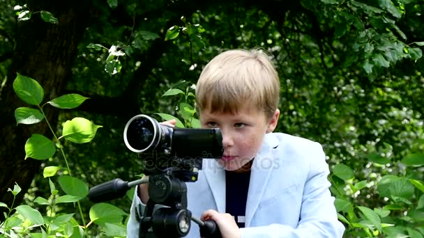 Jeune garçon regarde dans les tournages vidéo film sur la nature sur green park slow motion . — Video