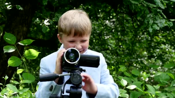 Fiatal fiú úgy néz ki, videó hajtások film természet zöld park lassú mozgás. — Stock videók