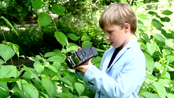 Junge mit Videokamera filmt in der Natur von grünem Park Zeitlupe. — Stockvideo