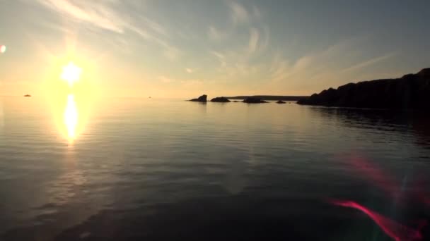 Rayos brillantes de puesta de sol en el cielo reflejados en la superficie del agua del Océano Ártico . — Vídeos de Stock