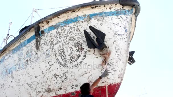 Arbetaren tvättar fartyget efter rengöring med slipskiva på varvet i hamn. — Stockvideo