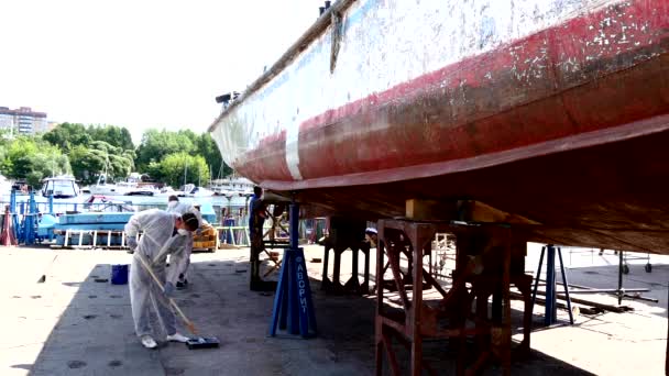 Рабочий покрывает металл грунтовой краской старого ржавого корабля на верфи в порту . — стоковое видео