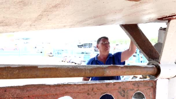 Worker paints with brush metal of rusty ship at shipyard in port of Moscow. — Stock Video