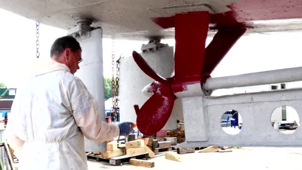 Trabalhador pinta metal de hélice de navio cor vermelha no estaleiro no porto de Moscou . — Vídeo de Stock