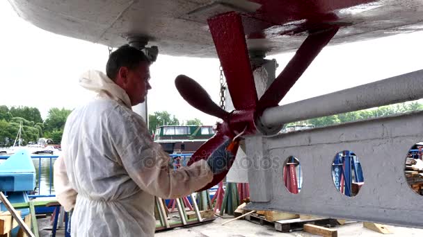 Travailleur peint métal de l'hélice de navire couleur rouge au chantier naval dans le port de Moscou . — Video